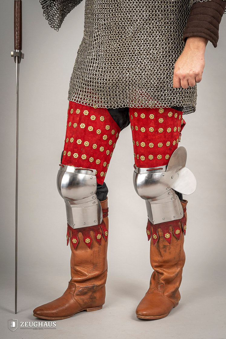 Armadura de piernas medieval en acero y piel roja