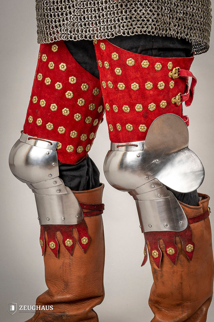 Armadura de piernas medieval en acero y piel roja